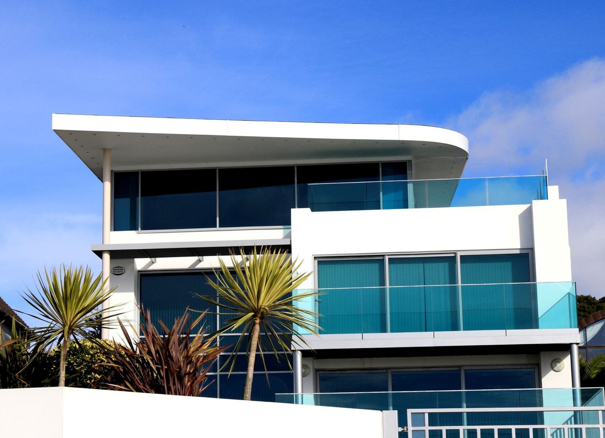 Modern white multi-storey building with glass balconies under a clear blue sky